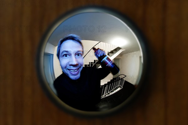 View through door viewer into a staircase of a big tenement, peephole, spyhole, with a man in front