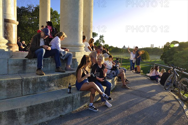 People enjoying the autumn sun at the Monopteros in the English Garden, with a view of the Munich