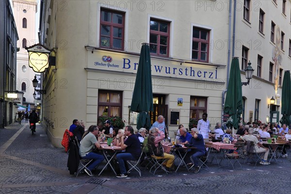 People sitting in the garden in front of the traditional restaurant Bratwurstherzl at