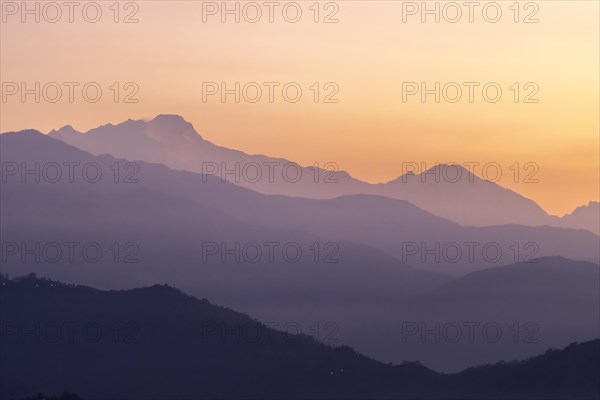 Silhouette of the Himalayan peaks, including Himalchuli and Baudha Himal, backlit by the orange
