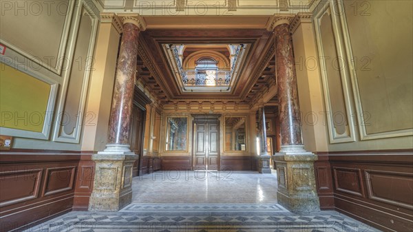 Symmetrical hallway with decorative ceiling and marble floor, flanked by columns, Villa Woodstock,