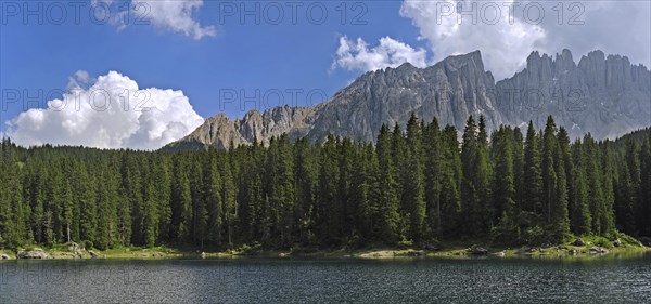 The lake Lago di Carezza, Karersee surrounded bij mountain peaks and pine forest in the Dolomites,