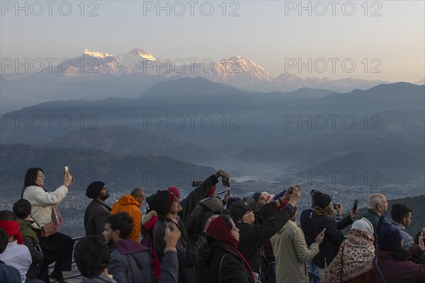 Asian-looking tourists watching and photographing sunrise as well as shooting selfies on the second