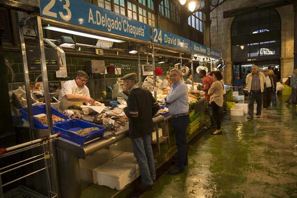People shopping at fishmonger stalls inside historic covered market building, Jerez de la Frontera,