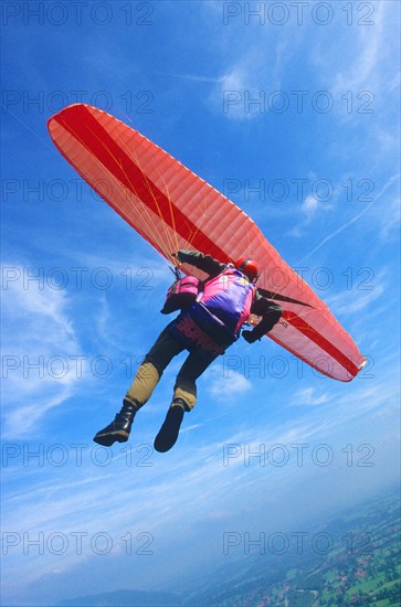 Paragliding pilot in a curve high above ground, camera on fishing lines fixed at the glider,