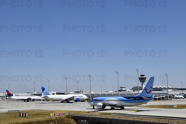 TUI Boeing B737-800 MAX taxiing on apron in front of Terminal 1 with tower, Munich Airport, Upper