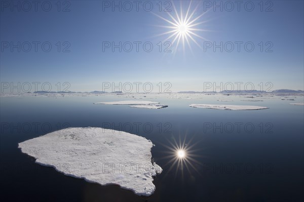 Midnight sun over the Arctic Ocean with drifting ice floes, north of the Arctic Circle at