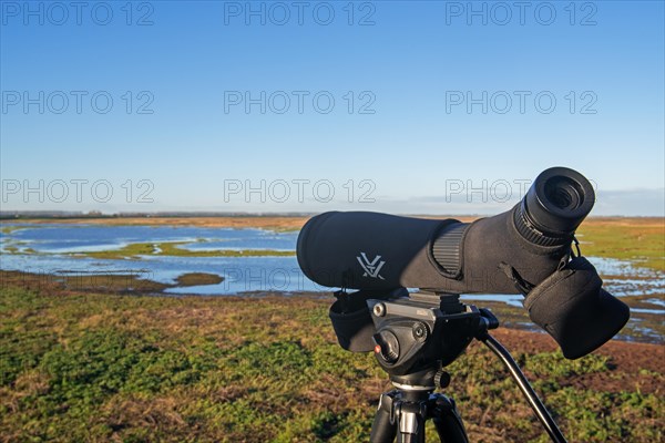 Birdwatcher's telescope and view over salt marsh of the Western Scheldt estuary at nature reserve