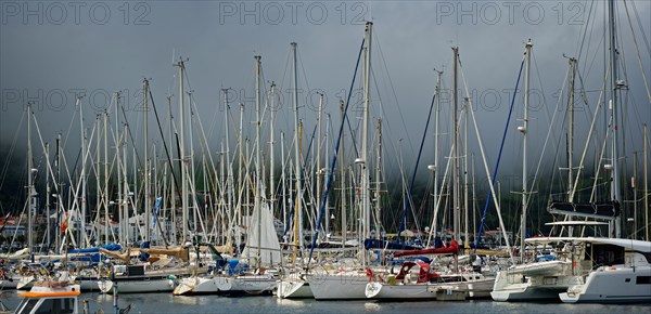 Sailboats in the sunny harbour of Horta with dark clouds above, Horta, Faial Island, Azores,