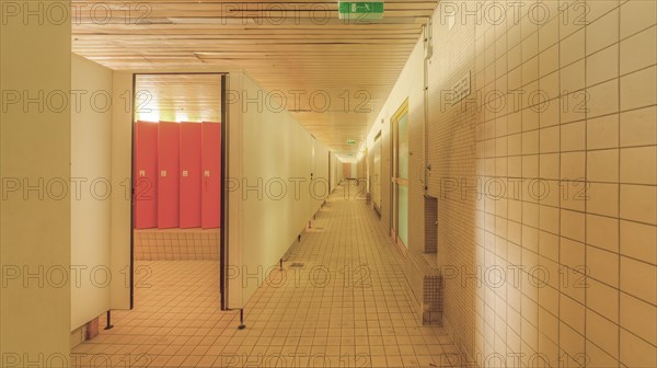 A corridor with tiled walls and doors on both sides leading to changing room lockers, Bad am Park,