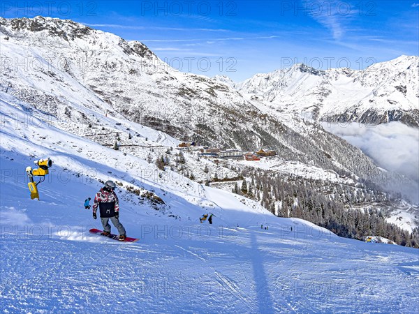 Snowboarders on the ski slope in front of the Hochsoelden hotel settlement in the Soelden ski