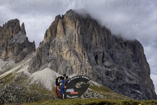 Traditional traditional costume couple advertising sign on the Sella Pass, behind Sassolungo, South