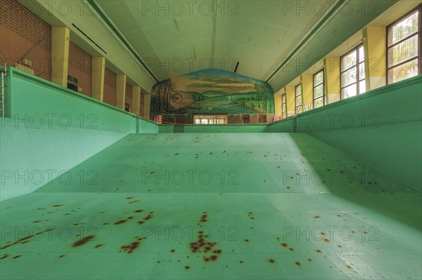A dilapidated, empty swimming pool with rust stains on the floor, deserted atmosphere, Bad am Park,