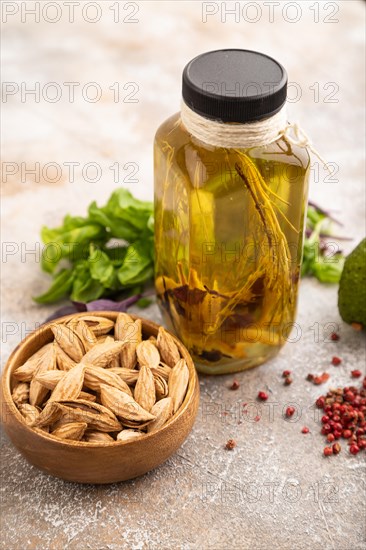 Sunflower oil in a glass jar with various herbs and spices, sesame, rosemary, avocado, basil,