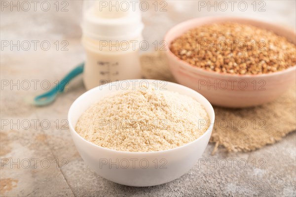 Powdered milk and buckwheat baby food mix, infant formula, pacifier, bottle, spoon on brown