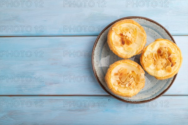 Traditional portuguese cakes pasteis de nata, custard small pies with almonds on blue wooden