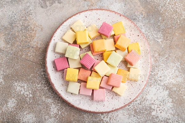 Various fruit jelly chewing candies on plate on brown concrete background. apple, banana,
