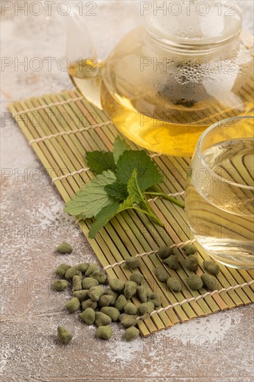 Green oolong tea with herbs in glass on brown concrete background. Healthy drink concept. Side