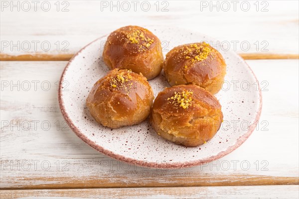 Homemade traditional turkish dessert sekerpare with almonds and honey on white wooden background.