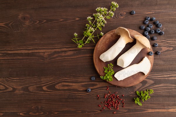King Oyster mushrooms or Eringi (Pleurotus eryngii) on brown wooden background with blueberry,
