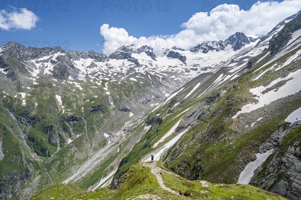 Mountaineer on hiking trail in picturesque mountain landscape, in the background mountain peak