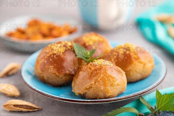 Homemade traditional turkish dessert sekerpare with almonds and honey, cup of green tea on gray