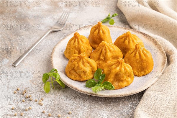 Fried manti dumplings with pepper, basil on gray concrete background and linen textile. Side view,