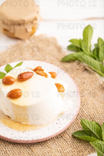 Ricotta cheese with honey and almonds on white wooden background and linen textile. side view,