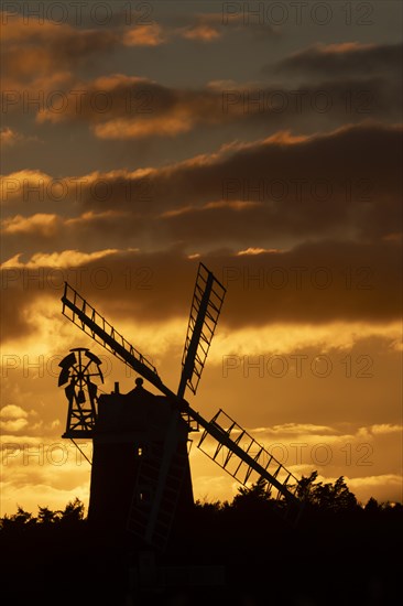 Windmill silhouetted at sunset with a red sky and clouds behind, Cley-next-to-the-sea, Norfolk,