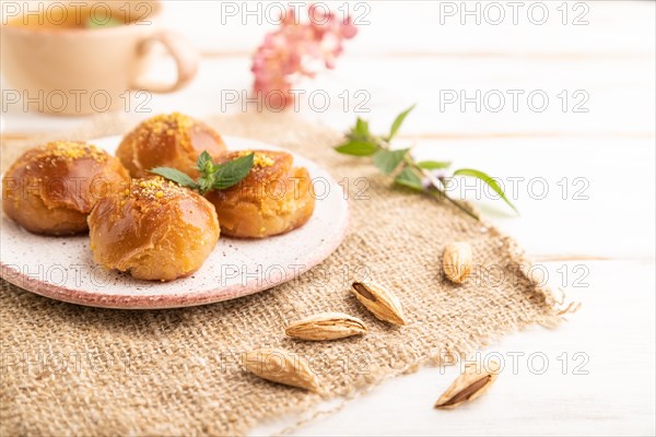 Homemade traditional turkish dessert sekerpare with almonds and honey, cup of green tea on white