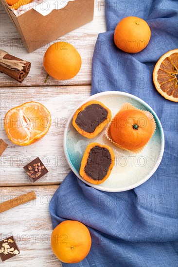 Truffle chocolate tangerine candies on a white wooden background and blue linen textile. top view,