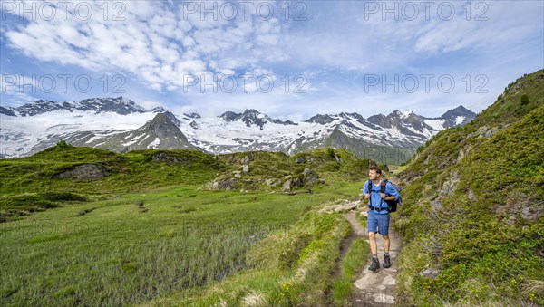 Mountaineer on hiking trail in picturesque mountain landscape, mountain peaks with snow and glacier
