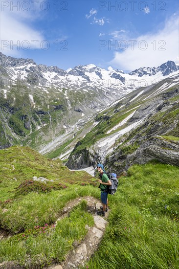 Mountaineer on hiking trail in picturesque mountain landscape, in the background mountain peak
