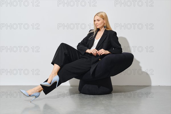 A professional woman in a chic outfit, seated confidently on a black bean bag, exuding elegance and