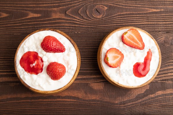 Grained cottage cheese with strawberry jam on brown wooden background. top view, flat lay, copy