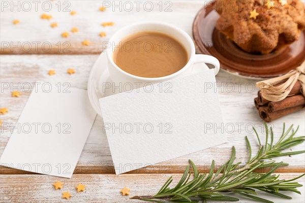 White paper business card mockup with cup of coffee and cake on white wooden background. Blank,