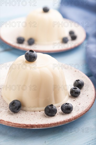 White milk jelly with blueberry on blue wooden background and blue linen textile. side view, close