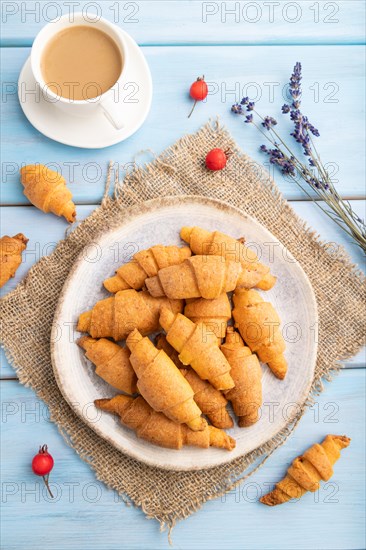 Homemade bagel roll with cup of coffee on a blue wooden background and linen textile. top view,