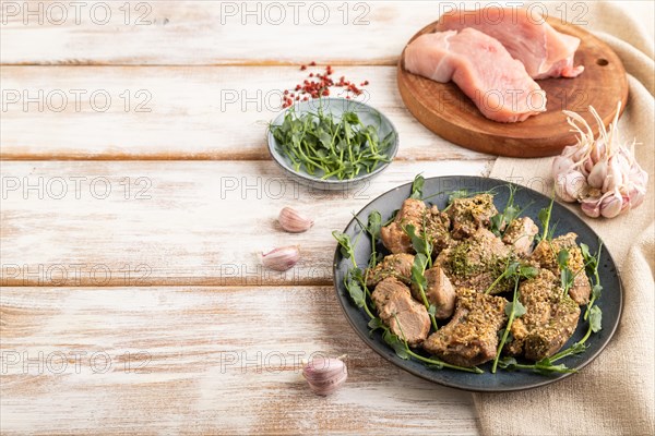 Stewed turkey fillet with garlic and sprouts of green peas on white wooden background and linen