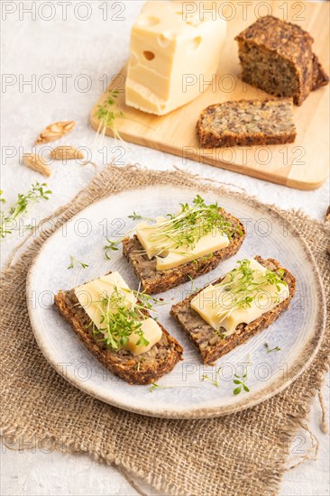 Grain bread sandwiches with cheese and watercress microgreen on gray concrete background and linen