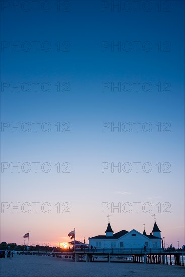 People strolling on a pier with buildings in the sunset, clear, blue, cloudless sky, pier Ahlbeck