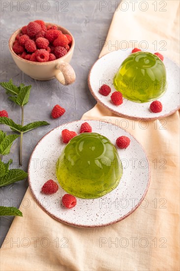 Mint and raspberry green jelly on gray concrete background and orange linen textile. side view,