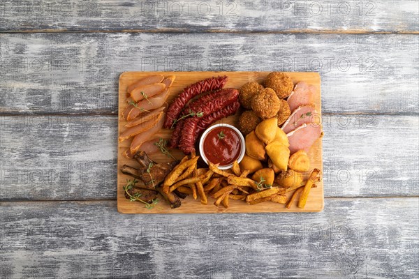 Set of snacks: sausages, fried potatoes, meat balls, dumplings, basturma on a cutting board on a