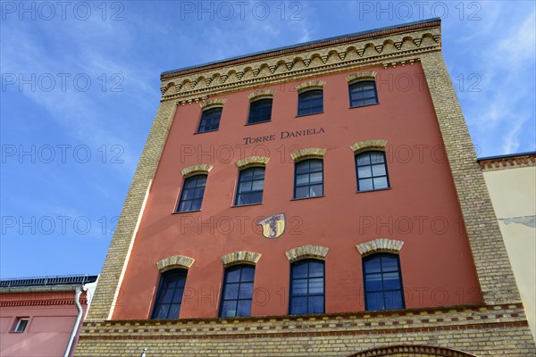 View of a historic red brick building with the nameplate 'Torres Daniela' under a blue sky, Torre