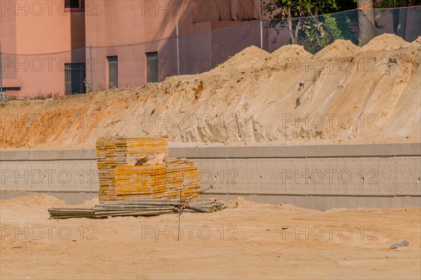 Concrete forms and iron scaffold pipes stacked neatly in front of concrete wall at construction