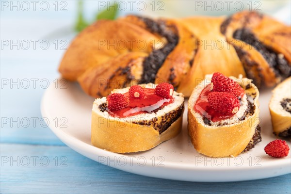 Homemade sweet bun with strawberry jam and cup of green tea on a blue wooden background. side view,