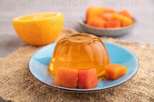 Papaya and orange jelly on gray concrete background and linen textile. side view, close up,