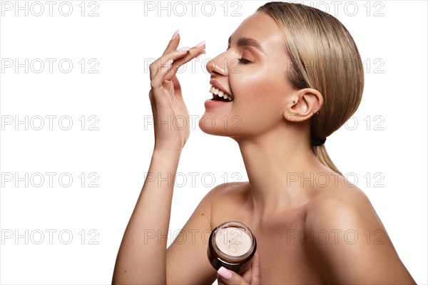 Beauty portrait of model with natural make-up holding a jar of cream. Fashion shiny highlighter on