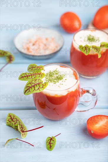 Tomato juice with sorrel, himalayan salt and sour cream in glass on blue wooden background with