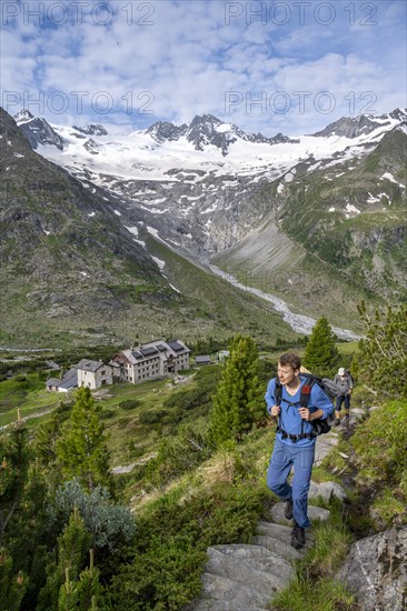 Two mountaineers on a hiking trail in a picturesque mountain landscape with alpine roses, in the